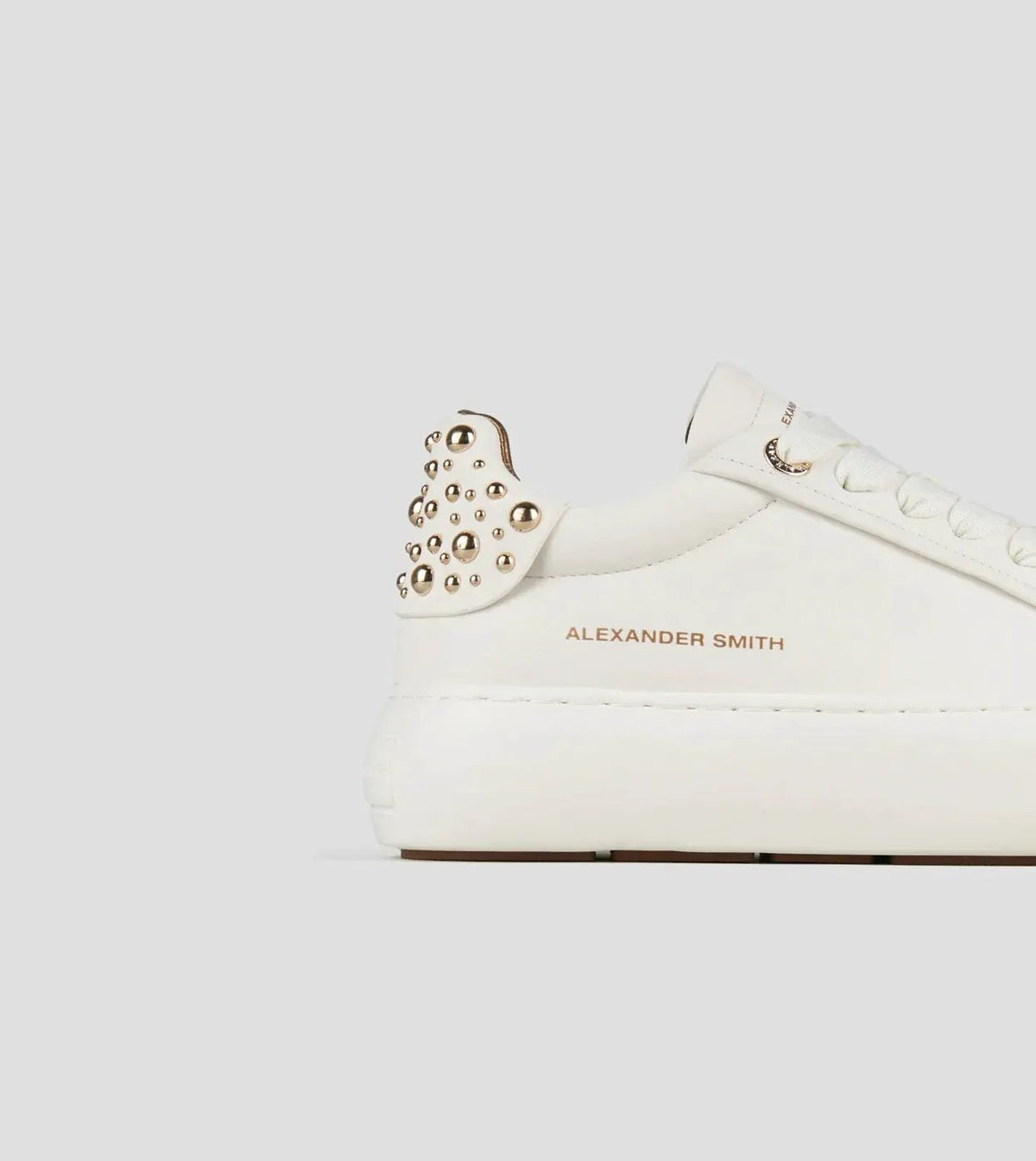 Sneaker donna in pelle bianca con borchie dorate sul tallone e suola platform