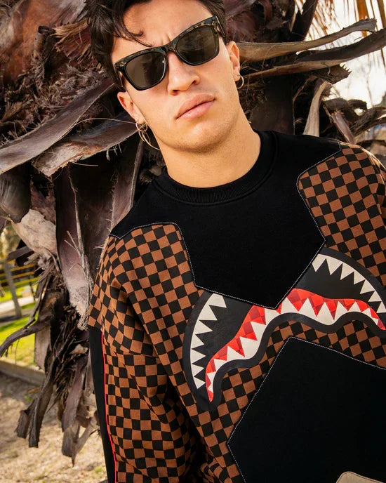 Uomo con occhiali da sole indossa felpa marrone e nera a quadri con motivo grafico dentato