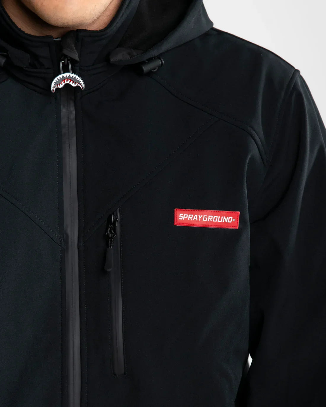 Giacca nera uomo in softshell con cappuccio e zip, dettaglio logo Sprayground rosso