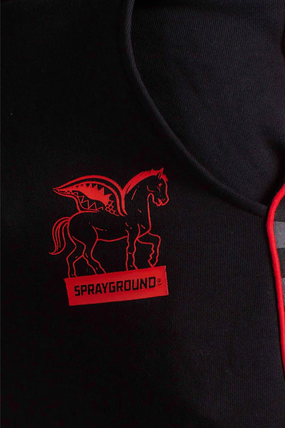 Dettaglio pantalone nero con logo rosso Sprayground e cavallo stilizzato, abbigliamento uomo.