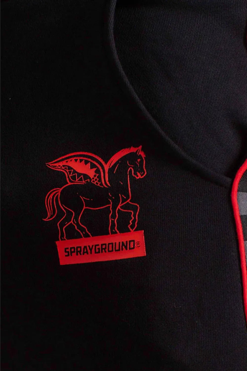 Dettaglio pantalone nero con logo rosso Sprayground e cavallo stilizzato, abbigliamento uomo.