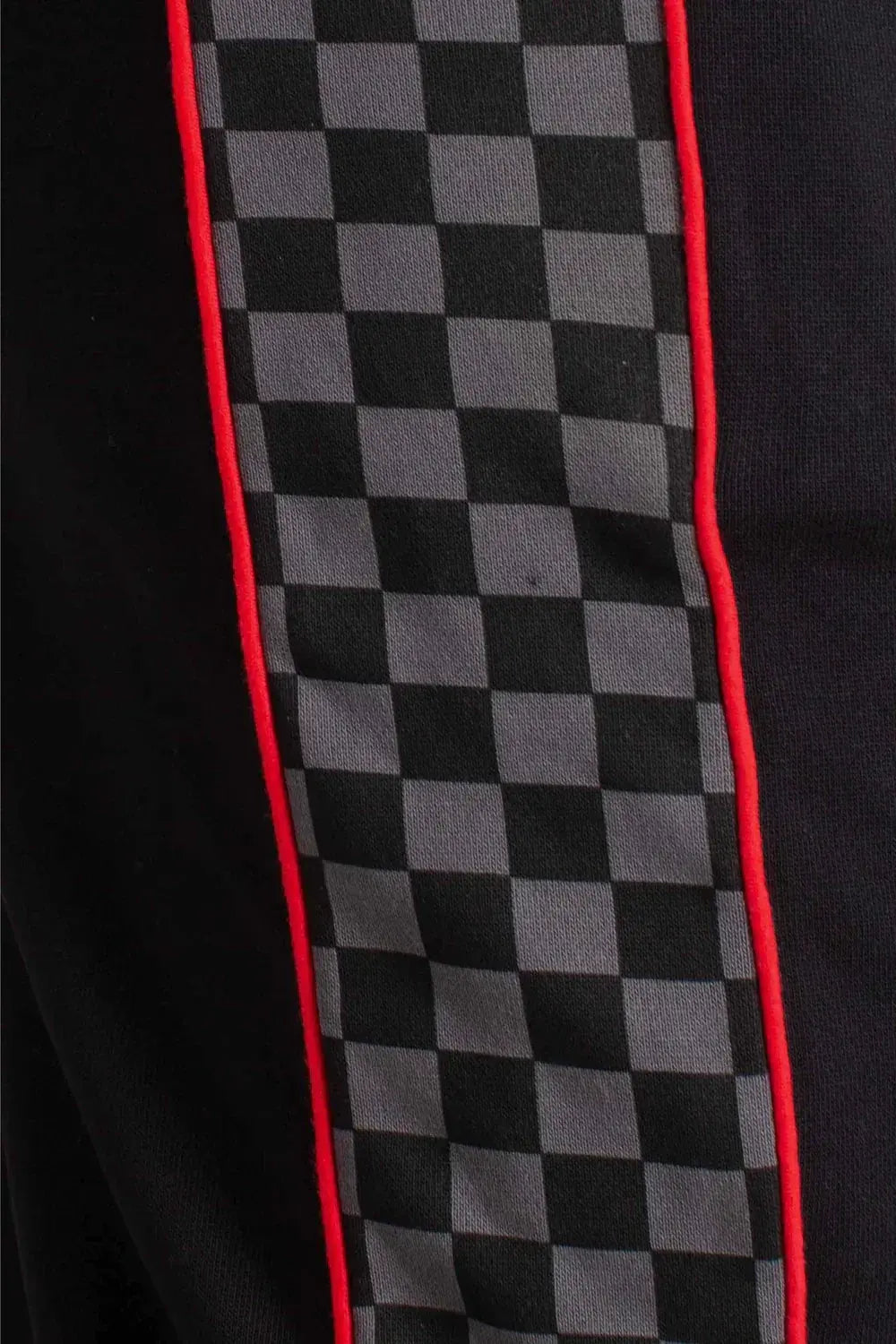 Dettaglio pantaloni neri con banda laterale a scacchi grigi e profili rossi, stile streetwear
