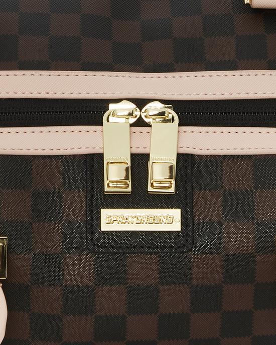 Dettaglio zaino a scacchi marrone con zip dorata e inserti beige, look moda accessori.