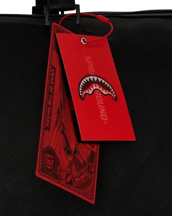Etichetta rossa con logo bocca di squalo su borsa nera in tessuto Sprayground