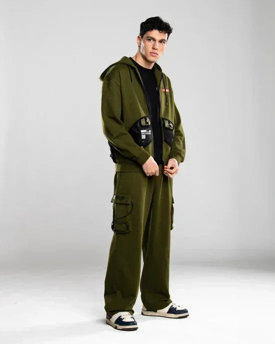 Uomo indossa completo streetwear verde militare con felpa con cappuccio e pantaloni cargo.