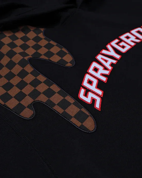 Dettaglio felpa nera con patch marrone a scacchi e scritta Sprayground in rosso.