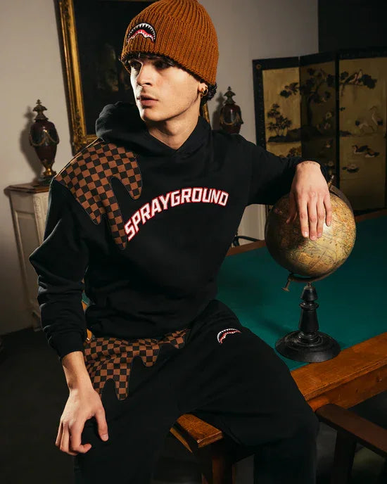 Modello con felpa nera Sprayground con dettagli a scacchi e scritta rossa, outfit streetwear