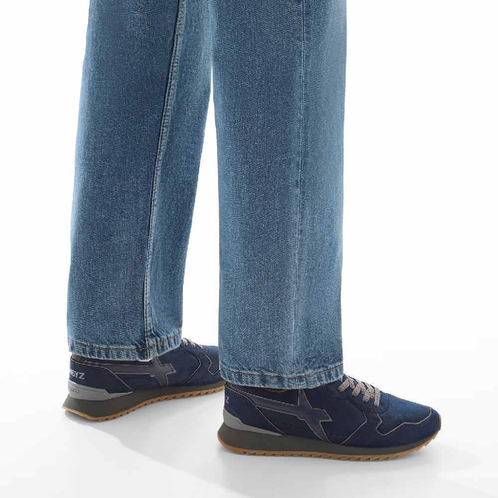 Sneakers uomo blu navy antracite con suola marrone, indossate con jeans larghi