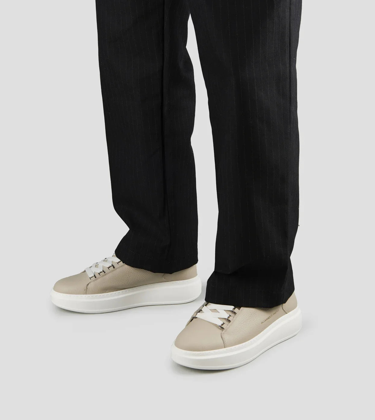 Sneakers uomo in pelle bottalata avorio con dettagli bianchi, indossate con pantaloni neri