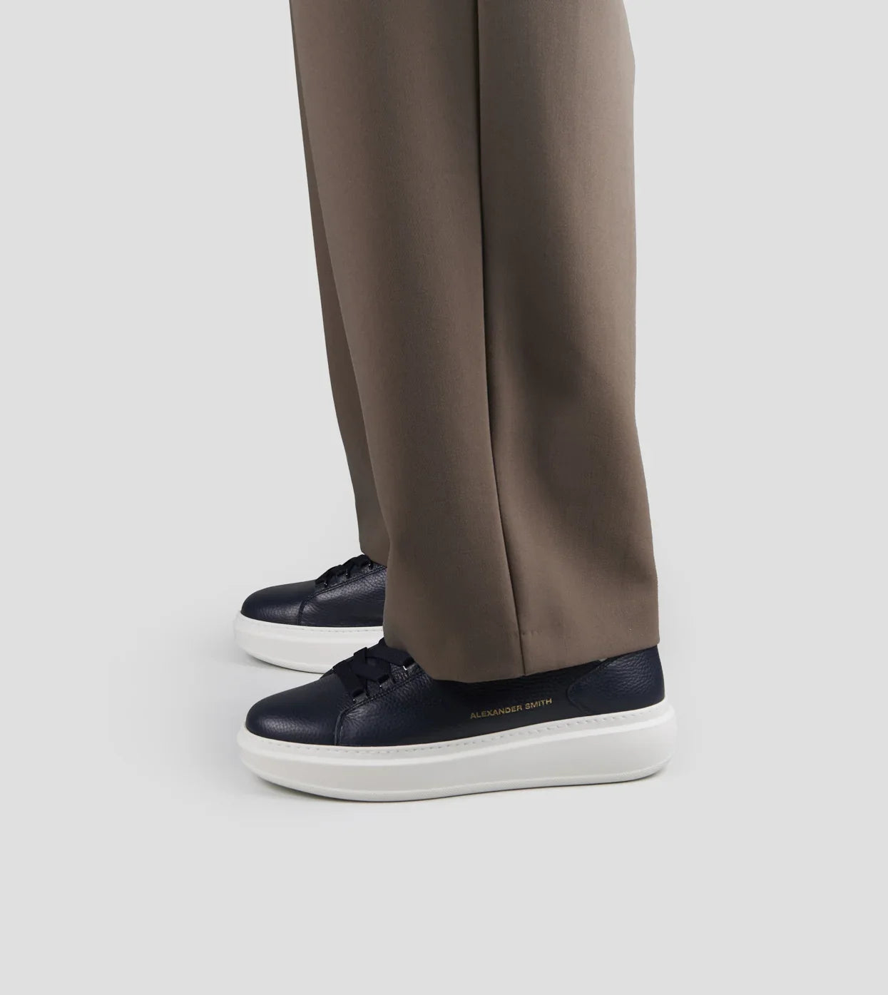 Sneaker uomo in pelle blu bottalata con dettagli bianchi, indossata con pantaloni beige.