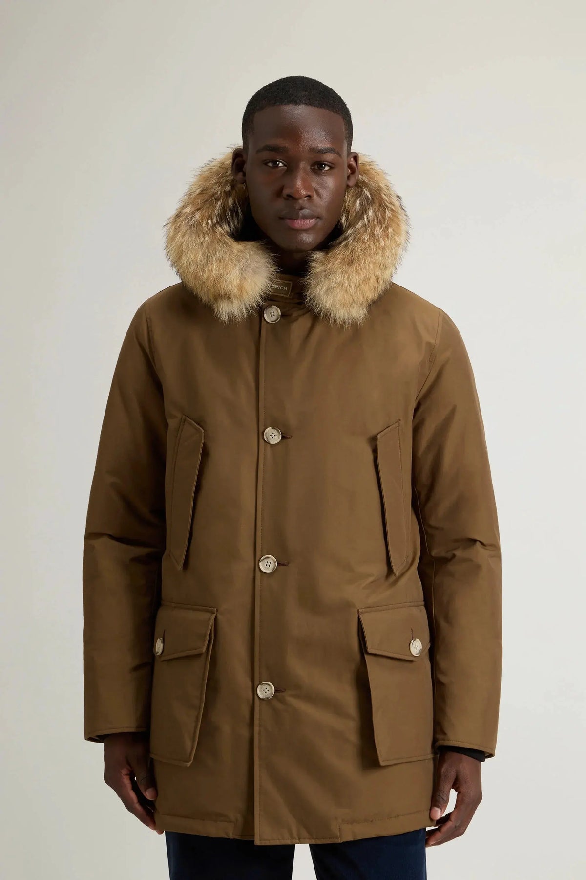 Modello indossa parka marrone con cappuccio e bordo in pelliccia, giacca invernale uomo elegante