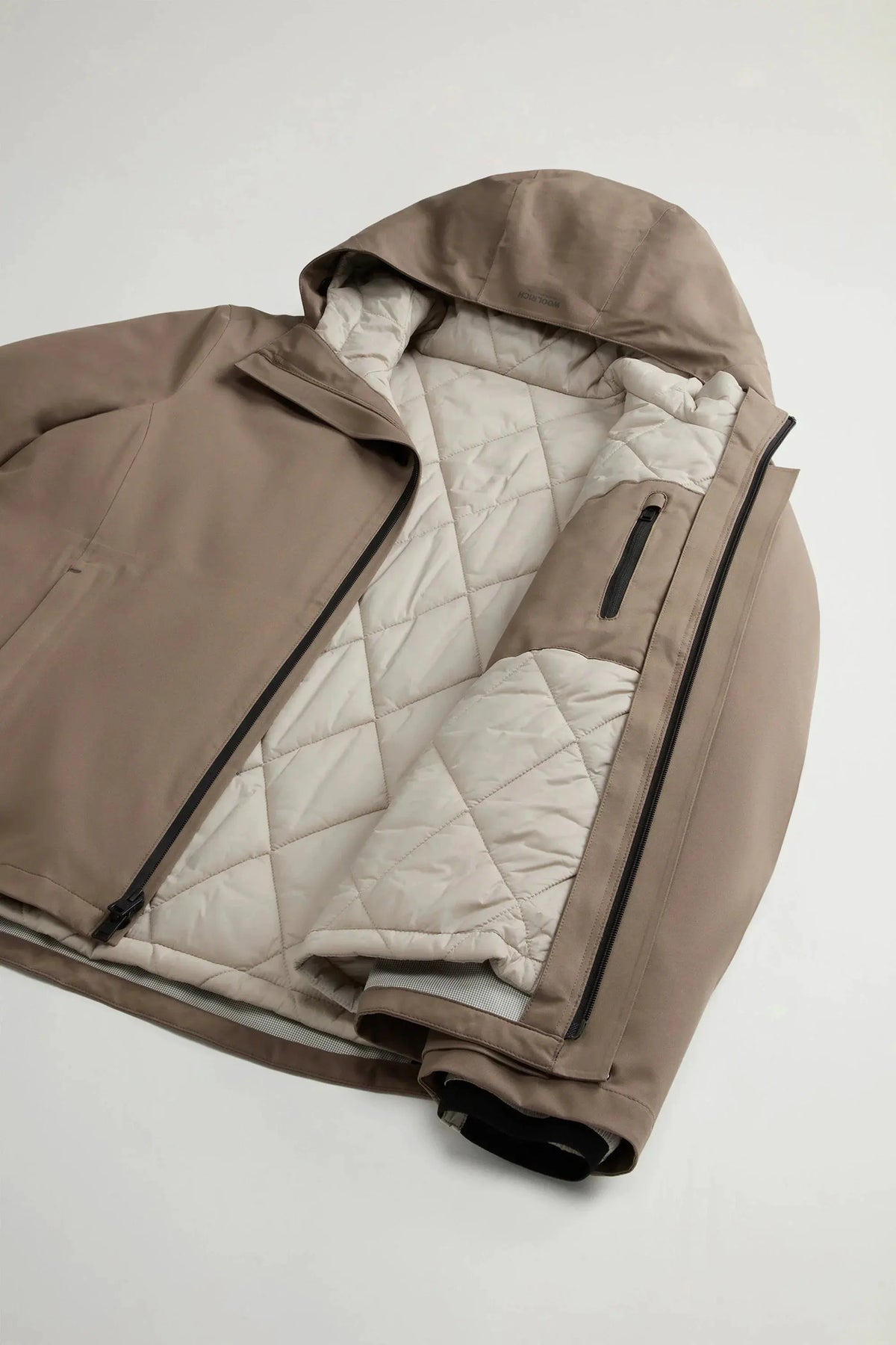 Giacca uomo beige con cappuccio e interno trapuntato, design sportivo e zip laterali.