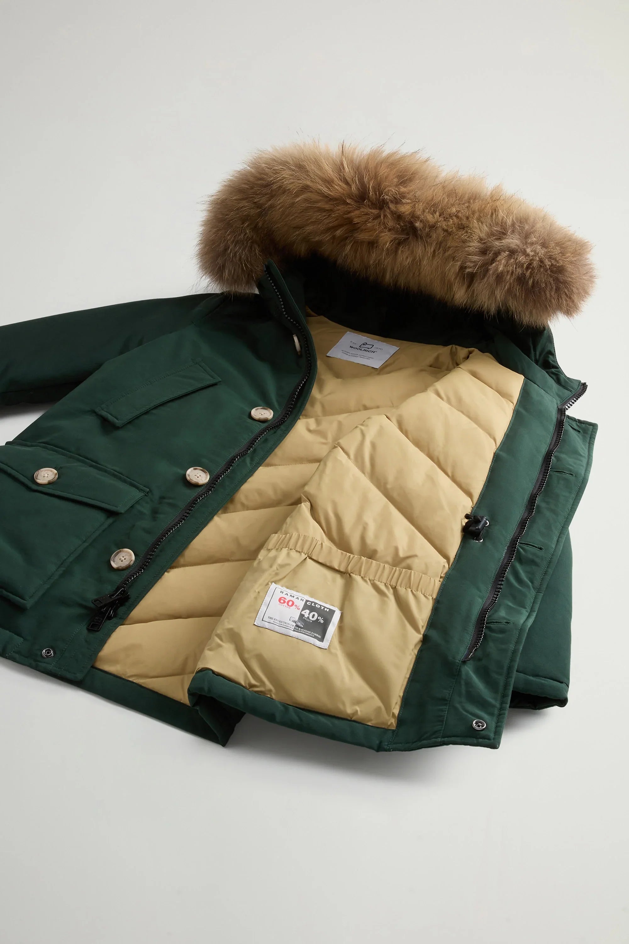 Parka verde bosco da uomo con cappuccio in pelliccia rimovibile e interno imbottito beige.
