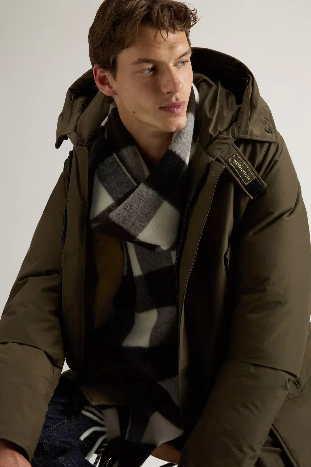 Uomo con parka verde con cappuccio e sciarpa a quadri, giacca invernale elegante.