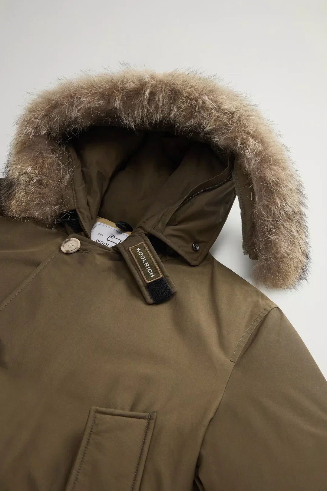 Parka verde con cappuccio e bordo in pelliccia removibile, dettaglio Woolrich visibile