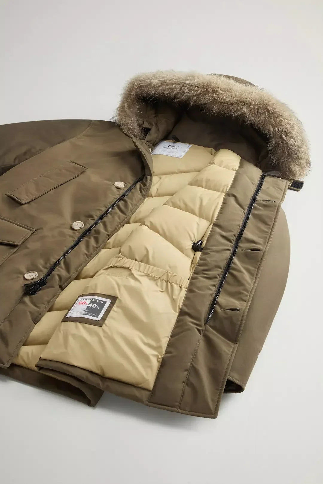 Parka invernale verde con interno trapuntato beige e cappuccio con bordo in pelliccia staccabile.