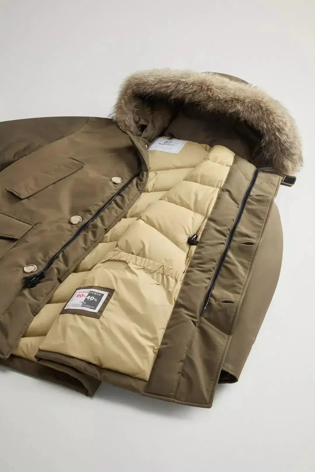 Parka invernale verde con interno trapuntato beige e cappuccio con bordo in pelliccia staccabile.