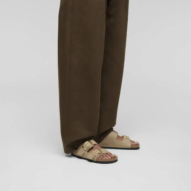 Pantaloni larghi marroni e sandali beige da uomo su sfondo neutro