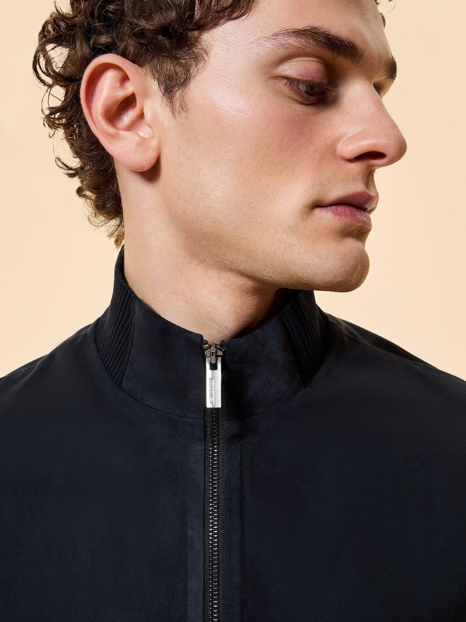 Primo piano di uomo con giacca nera elegante zip, collo alto, moda uomo Made in Italy.