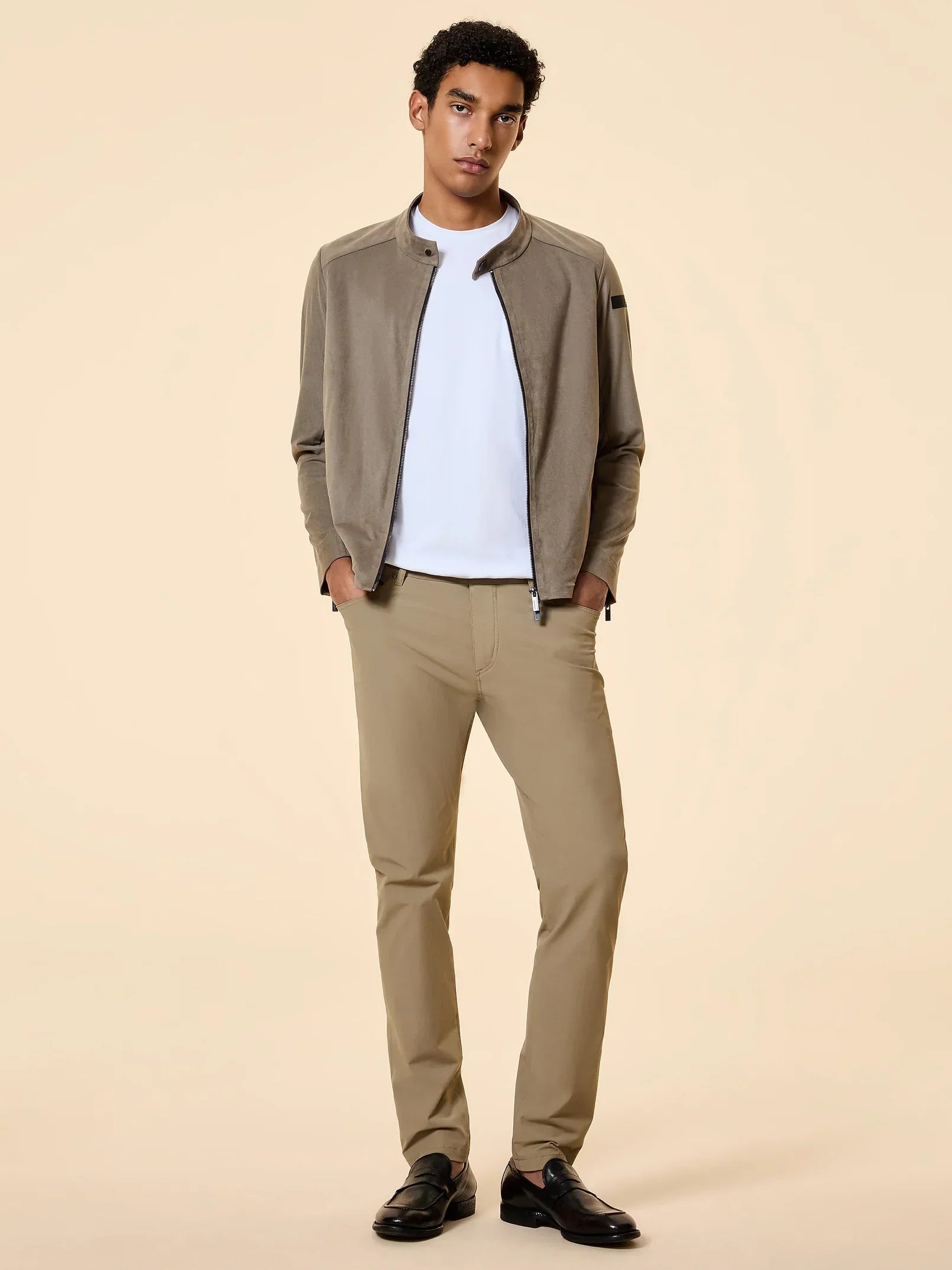 Modello uomo con giacca beige, t-shirt bianca, pantaloni beige e mocassini neri elegante