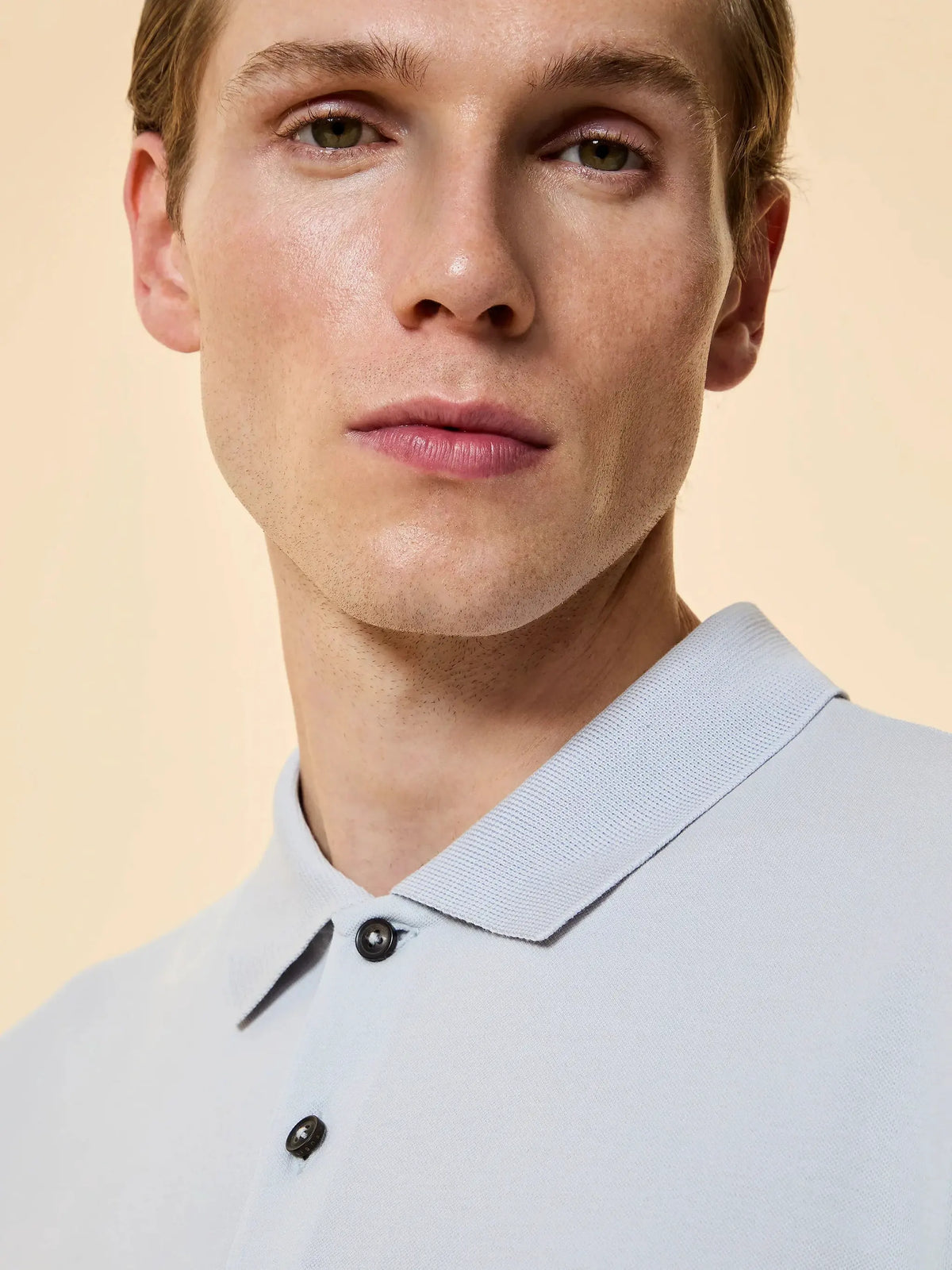 Primo piano uomo con polo celeste, colletto classico, bottoni neri, moda uomo elegante