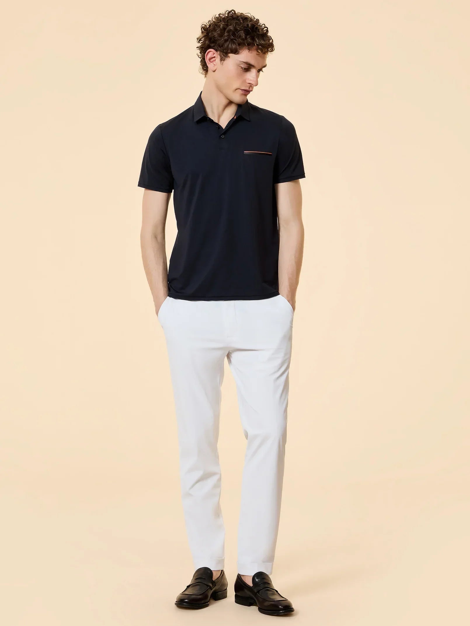 Uomo con polo blu scuro, pantaloni bianchi e mocassini neri, moda elegante uomo