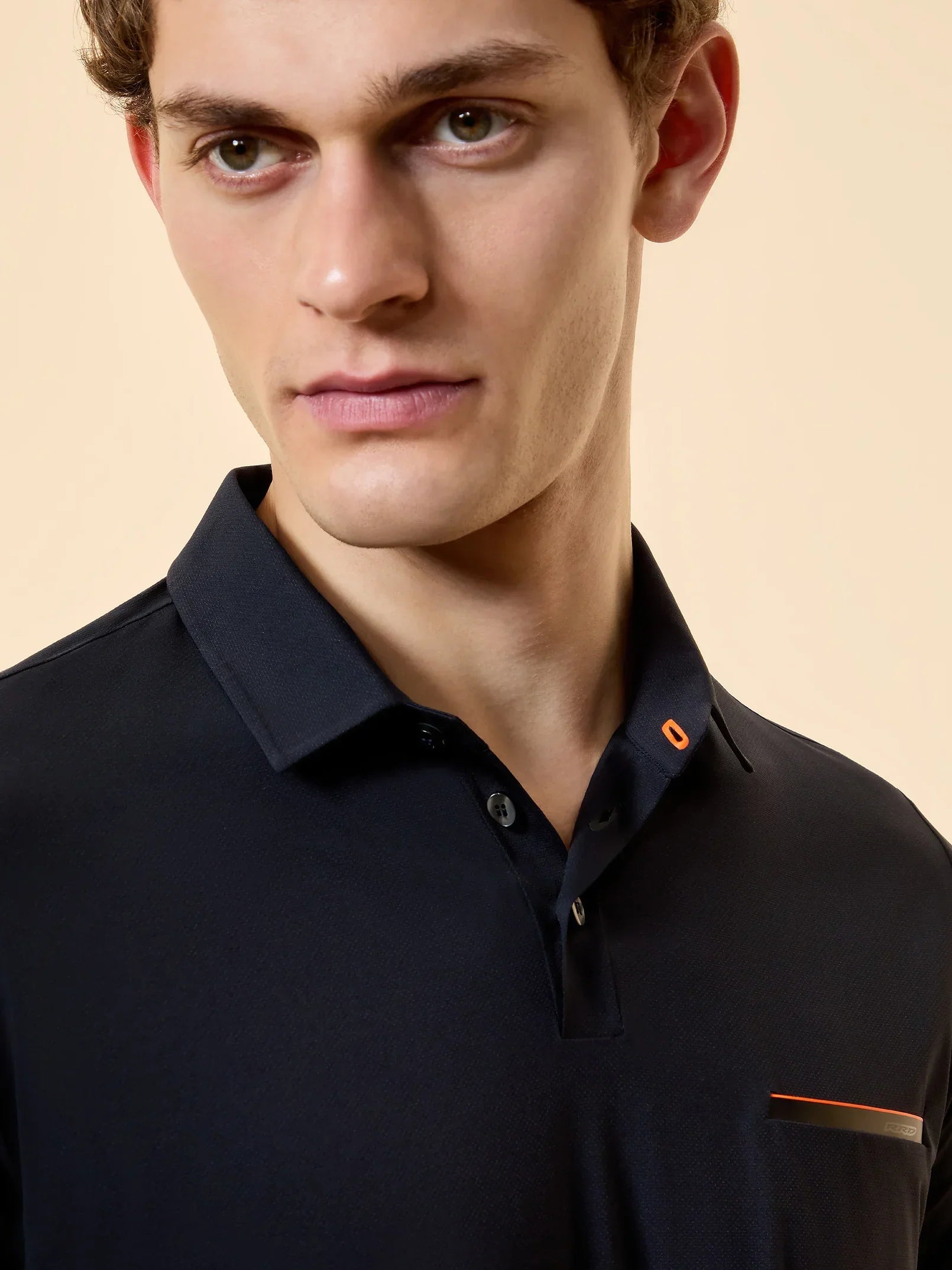 Uomo con polo blu scuro da uomo elegante con dettagli arancioni, moda abbigliamento maschile.