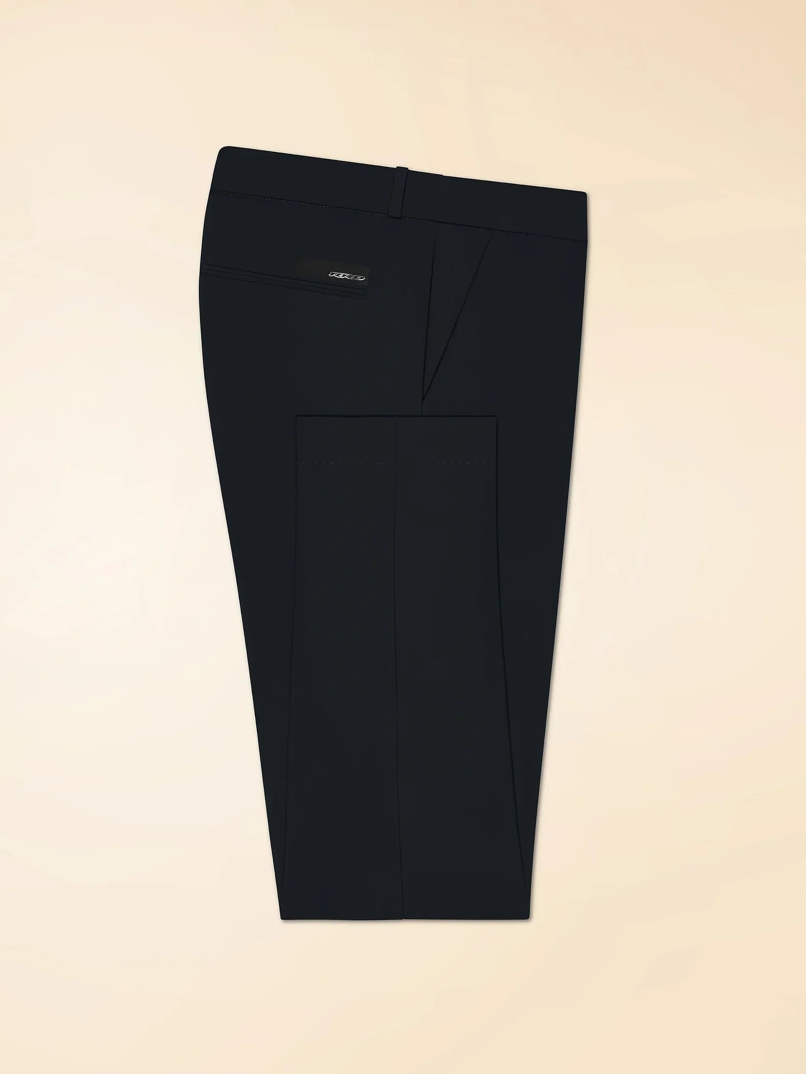 Pantaloni uomo neri eleganti piegati, tasca posteriore con dettaglio discreto, fondo beige.