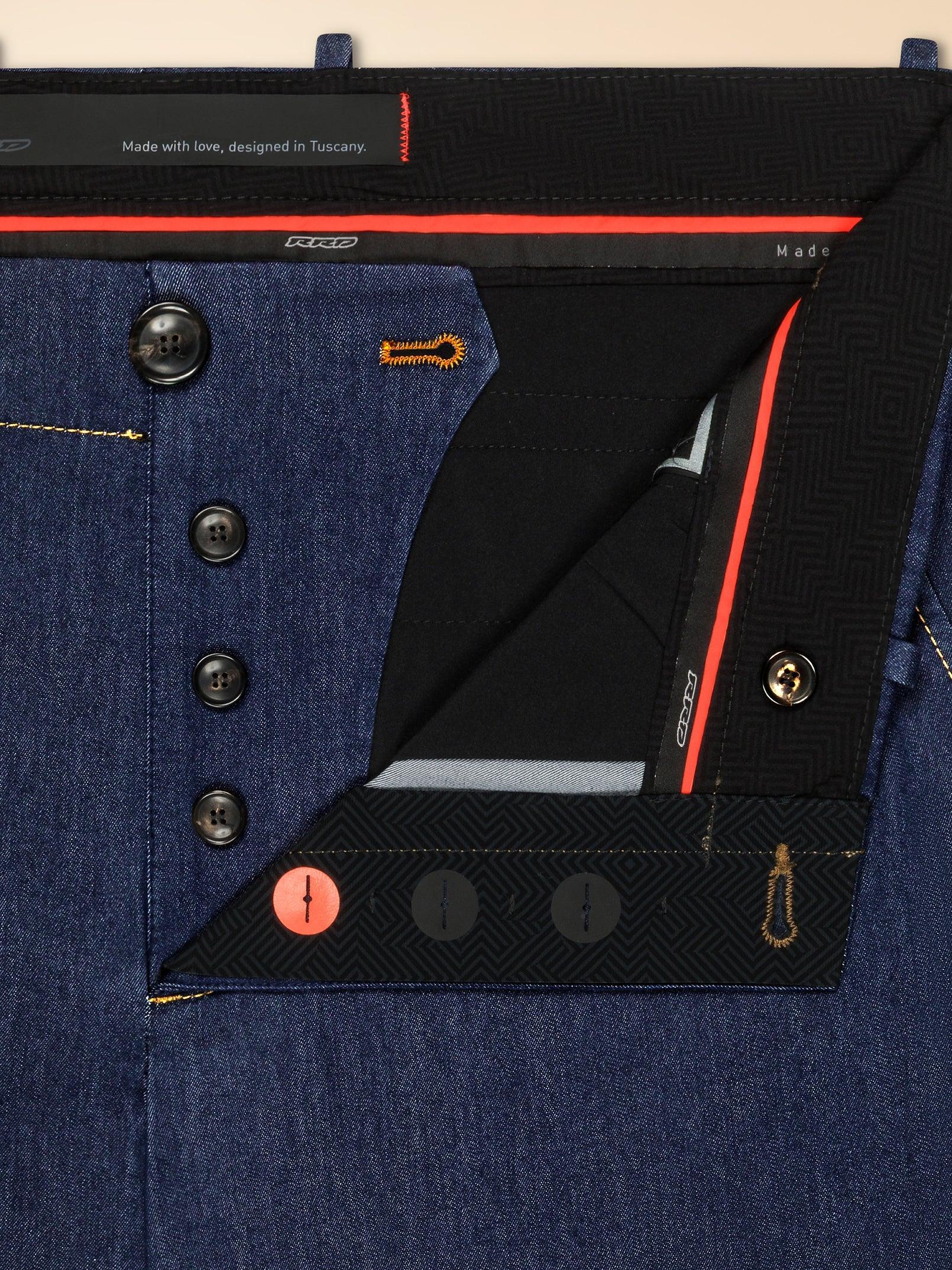 Dettaglio primo piano di pantaloni uomo in denim con bottoni neri e impunture a contrasto.