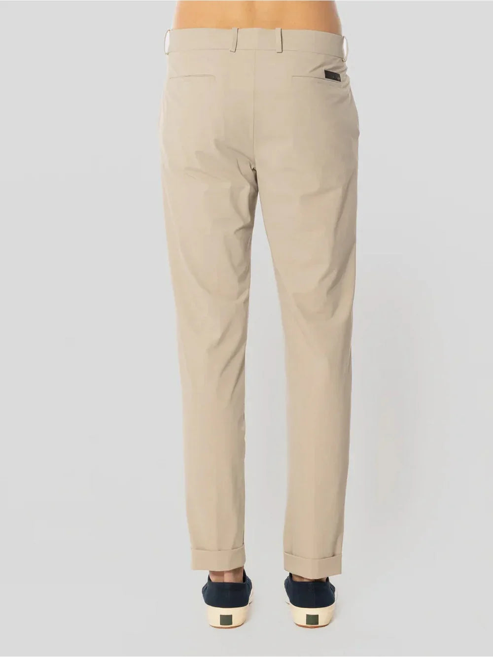 Pantaloni chino beige uomo eleganti, tasche posteriori e risvolto, su sfondo neutro.