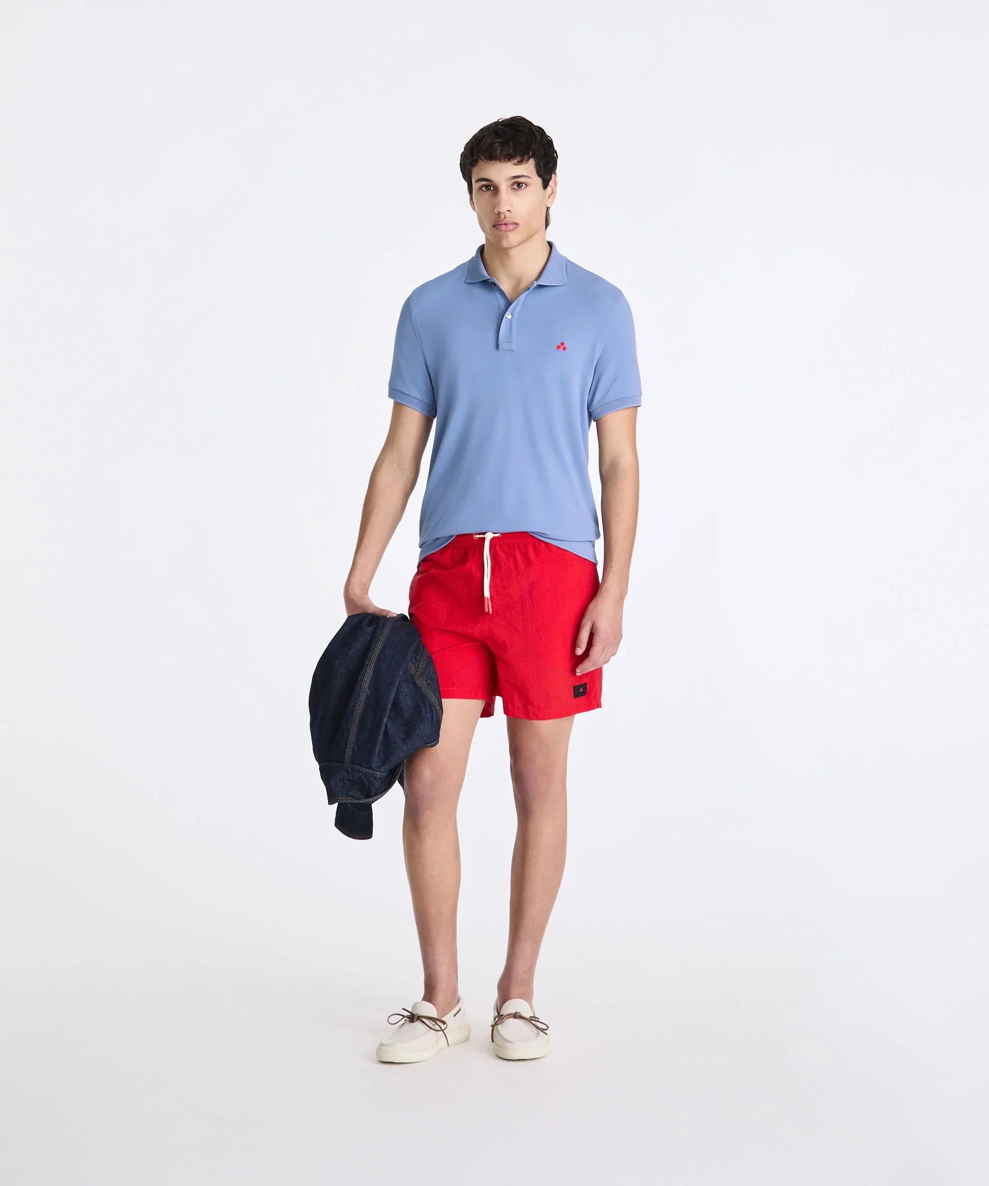 Uomo con polo azzurra, shorts rossi e mocassini bianchi, stile casual estivo