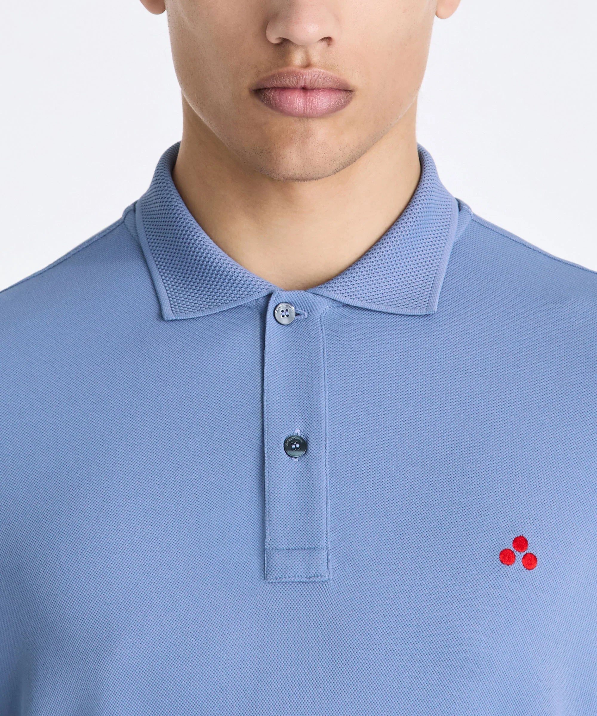 Polo uomo azzurra in cotone con piccolo logo rosso ricamato, colletto classico e bottoni.