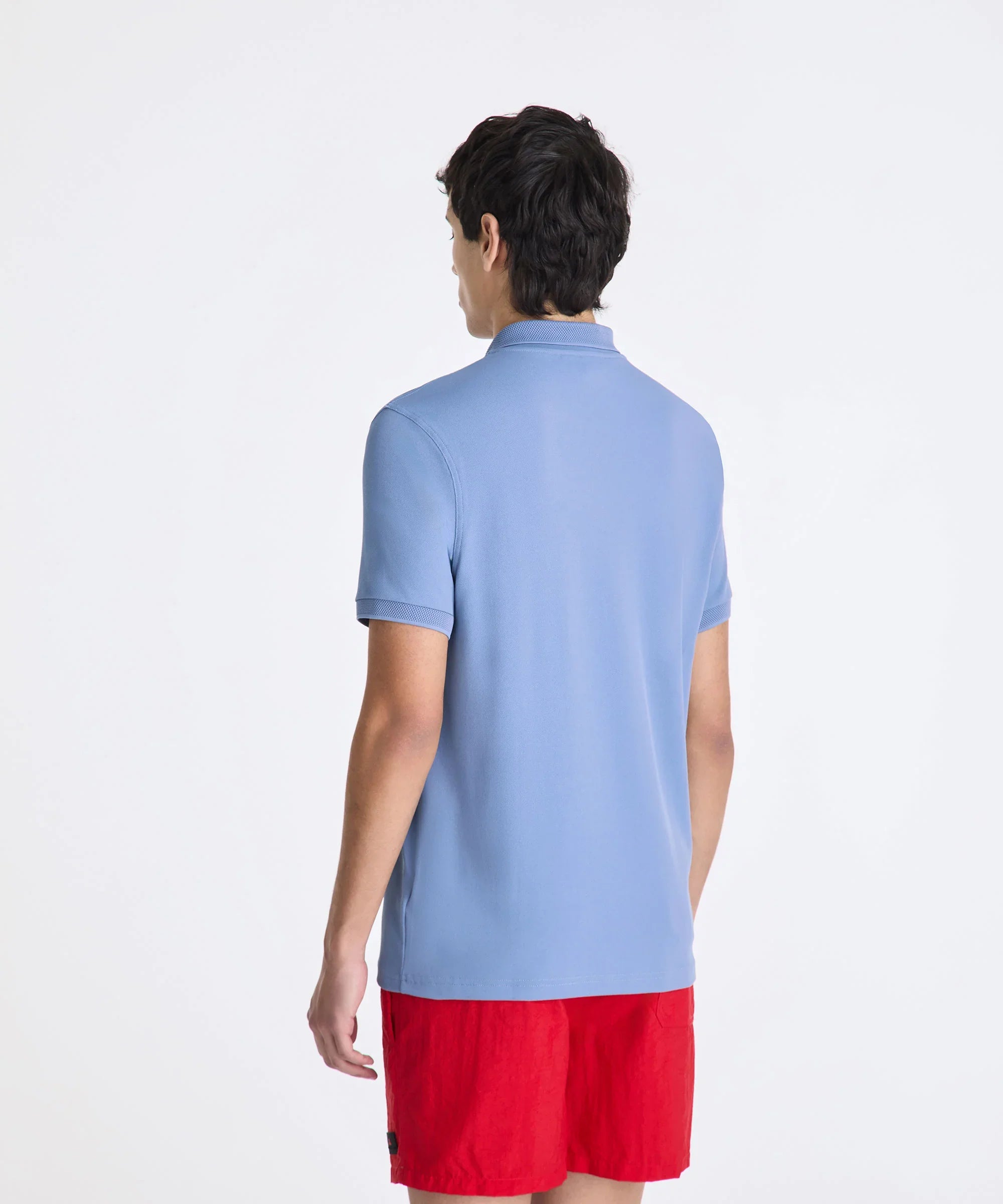 Uomo di spalle con polo azzurra e bermuda rossi, abbigliamento casual estivo