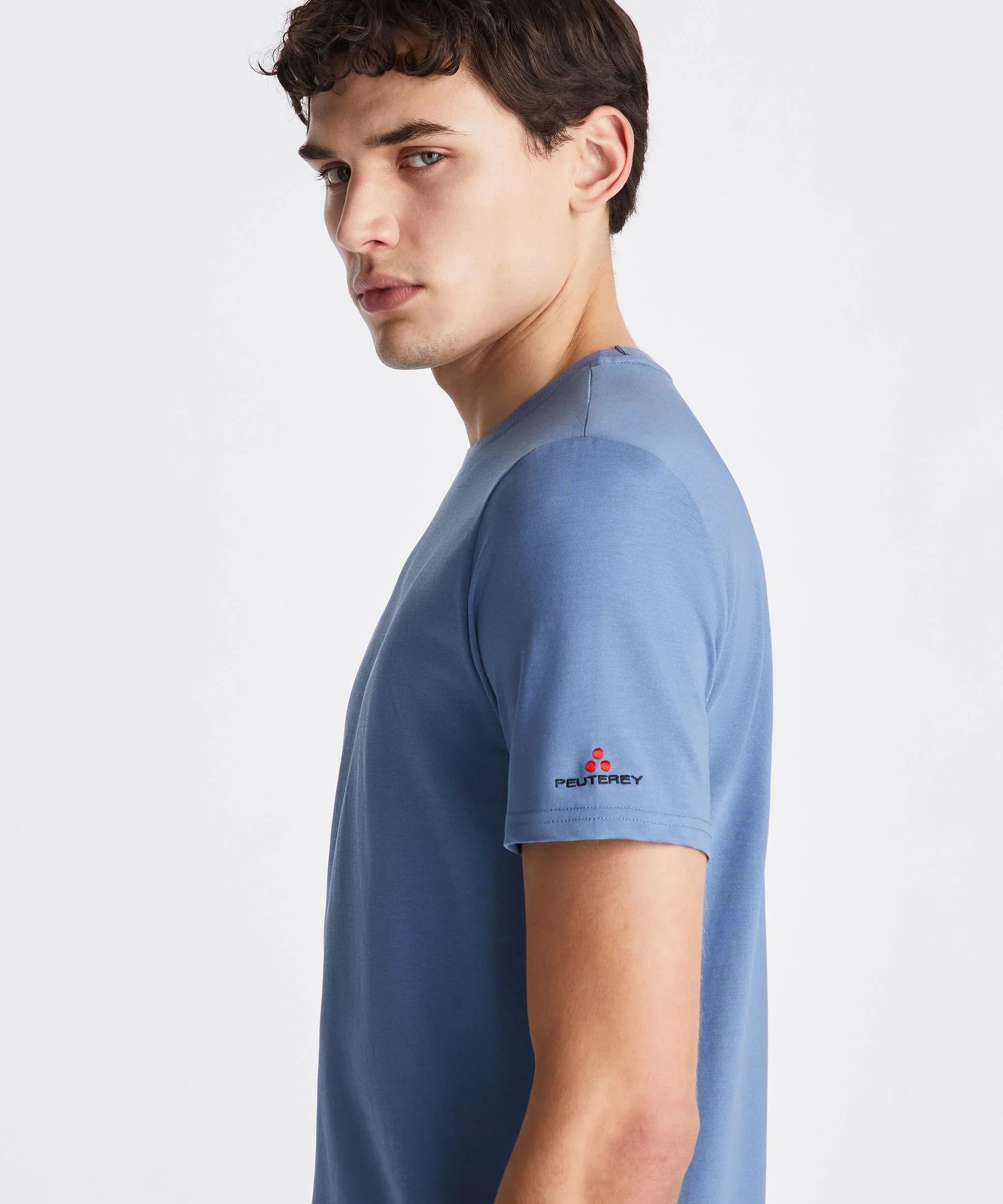 Uomo indossa t-shirt blu Peuterey in cotone, logo sulla manica, sfondo bianco