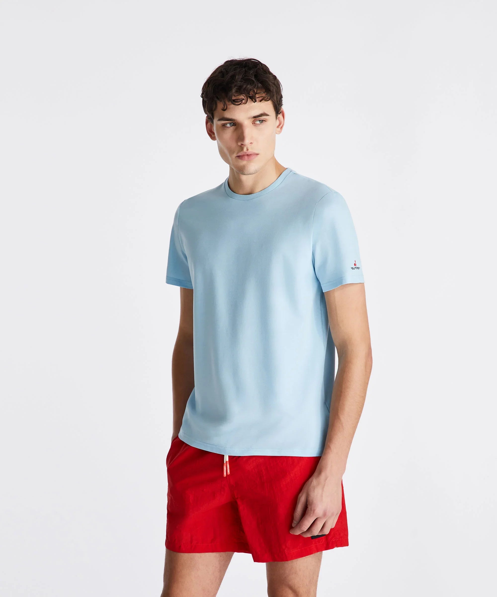 Modello indossa t-shirt azzurra manica corta e pantaloncini rossi da uomo