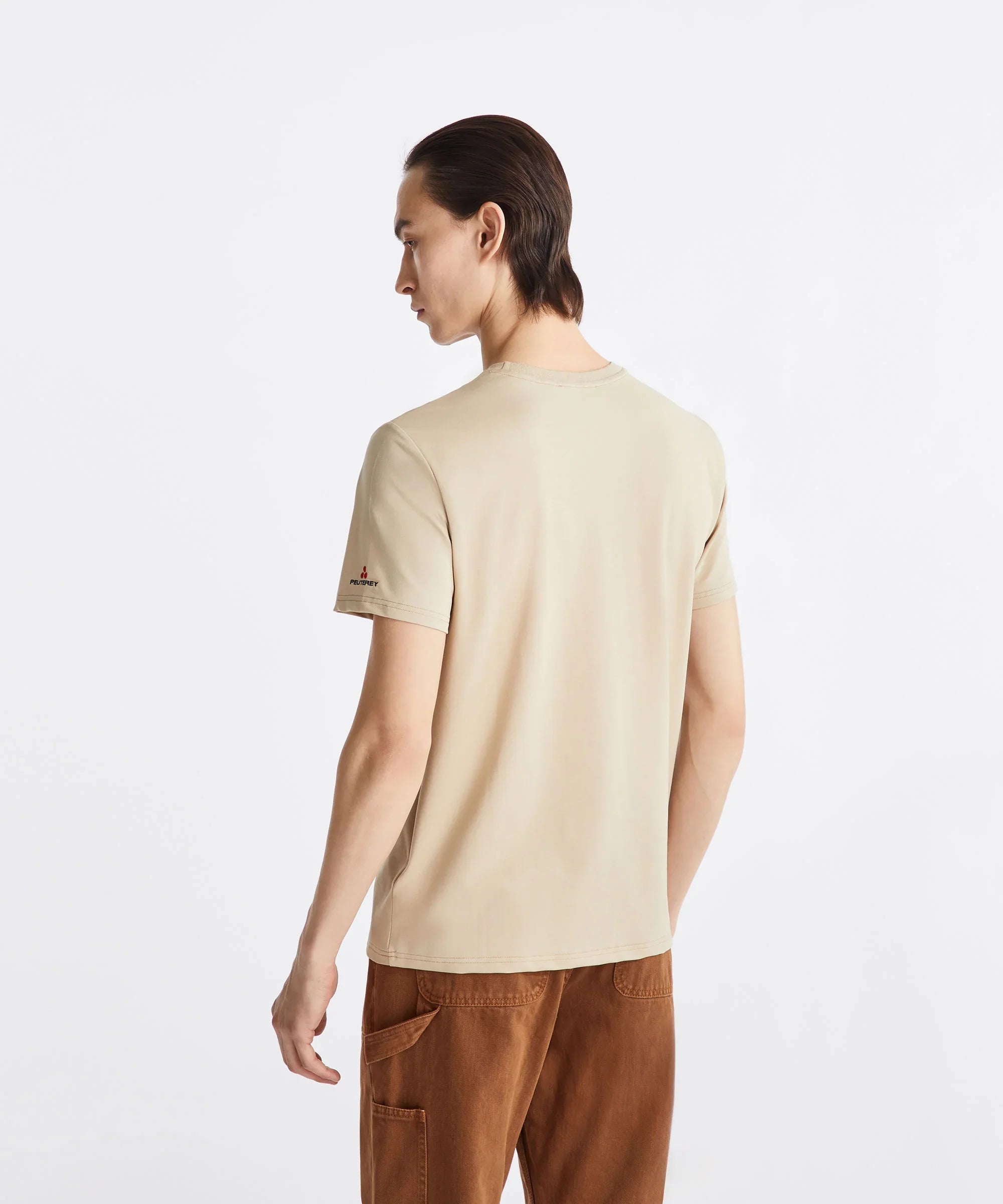 Maglietta uomo beige a maniche corte, pantaloni marroni, vista posteriore su sfondo bianco