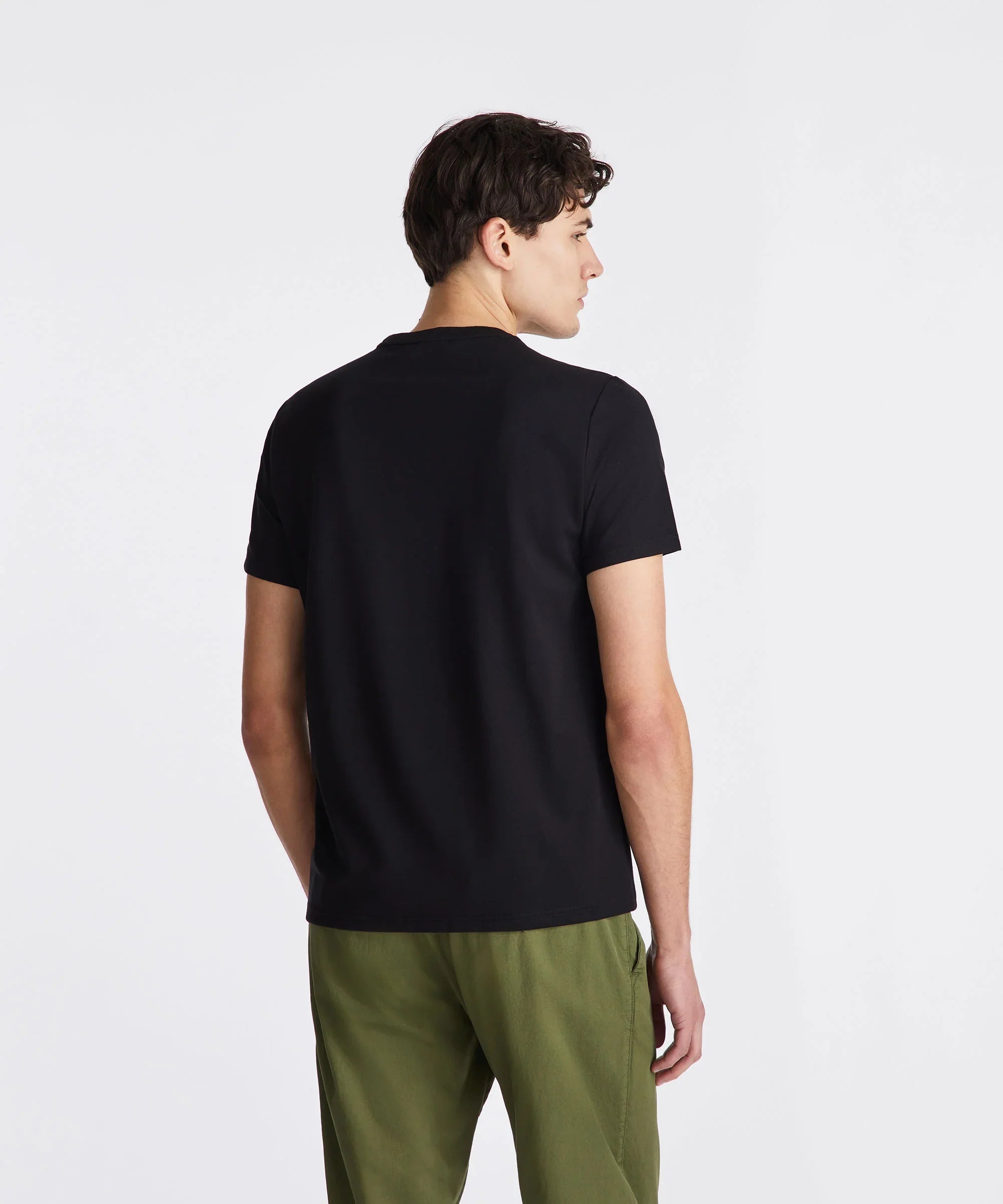 Modello uomo di spalle con t-shirt nera e pantaloni verdi, abbigliamento casual.
