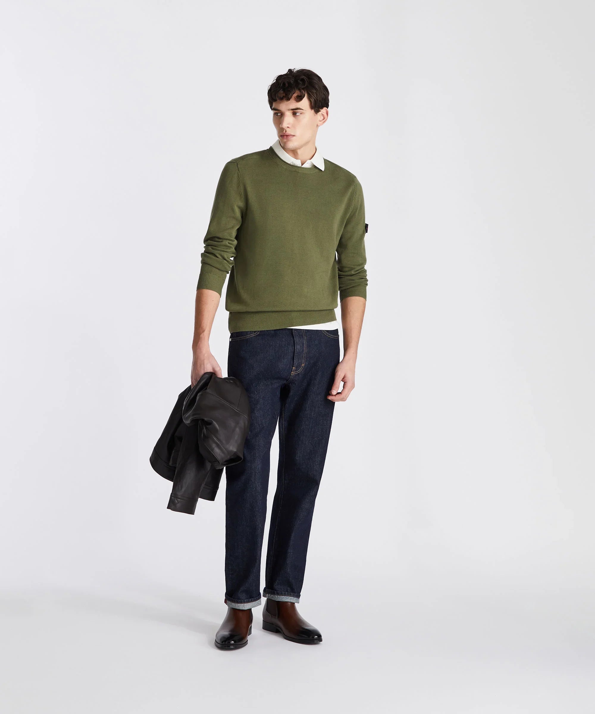Modello uomo indossa maglione verde, jeans blu e stivali marroni, stile casual elegante