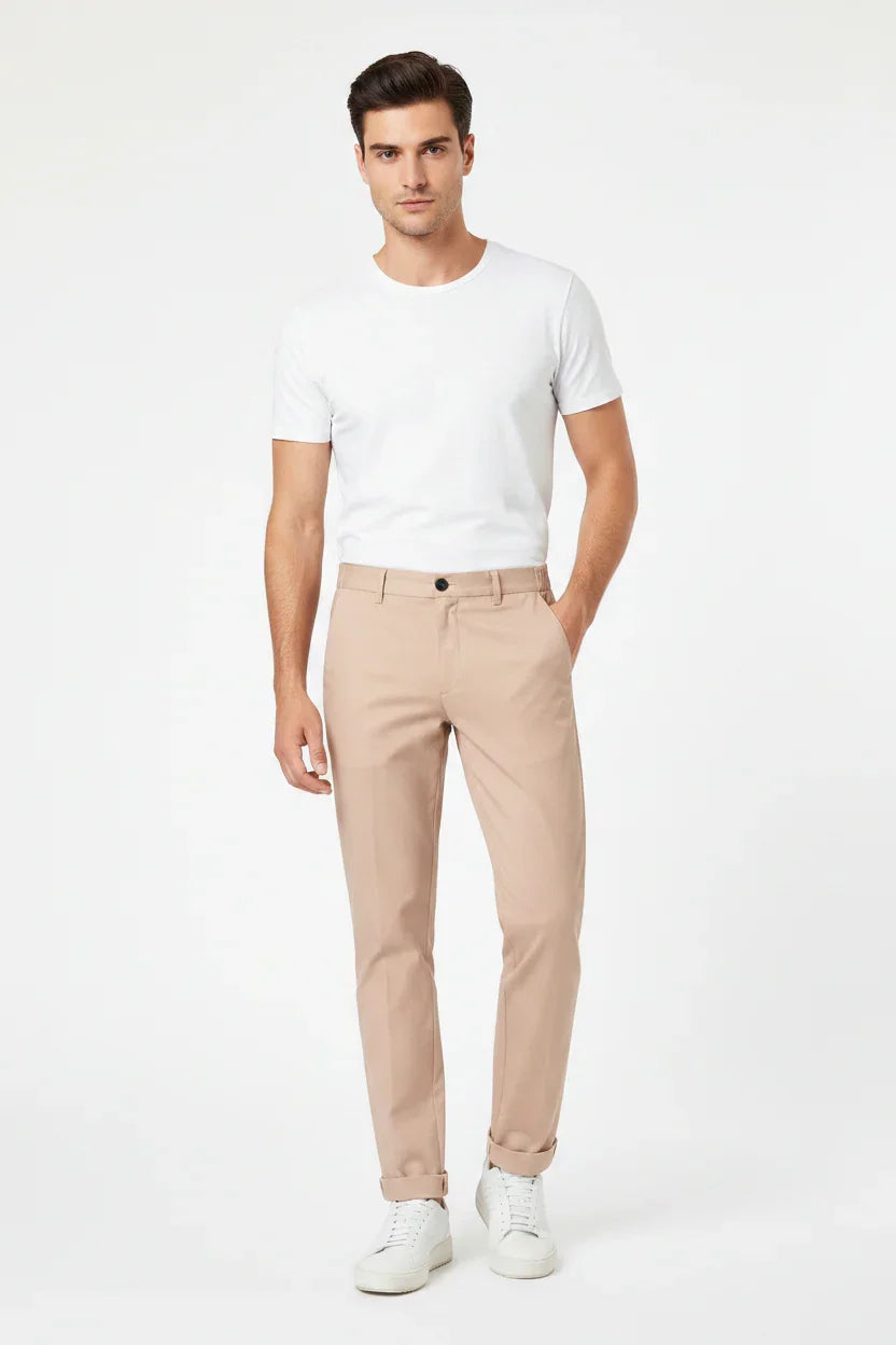 Modello uomo con pantaloni beige slim fit, t-shirt bianca e sneakers, look casual elegante