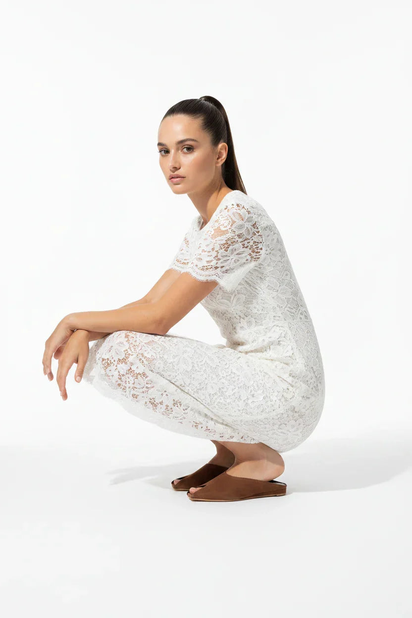 Donna con tuta in pizzo bianco a maniche corte e sabot marroni, sfondo bianco