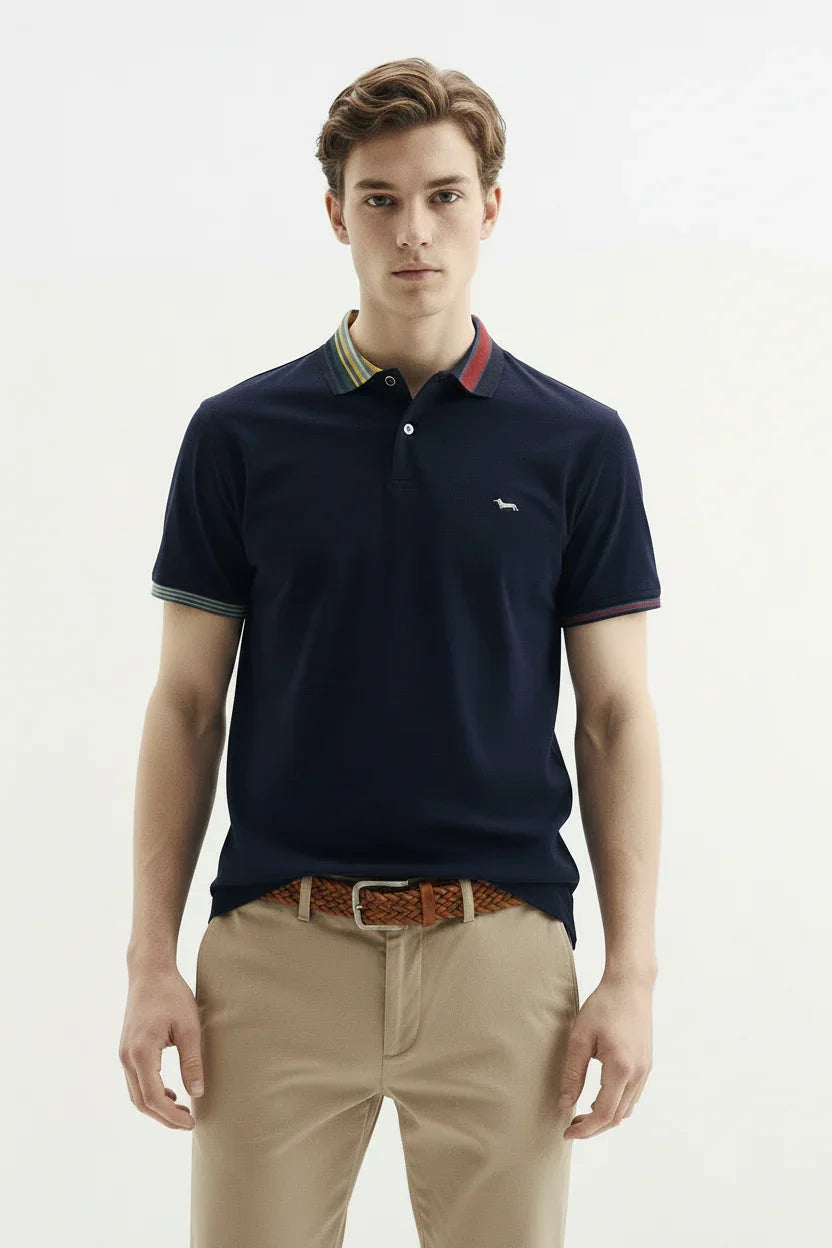Modello indossa polo blu navy con colletto a righe colorate e pantaloni beige uomo elegante