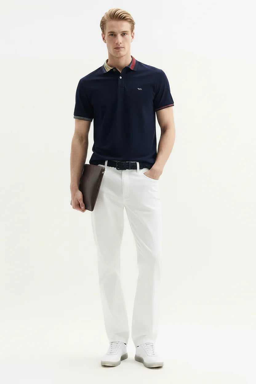 Modello uomo indossa polo blu, pantaloni bianchi e sneakers eleganti, look casual chic
