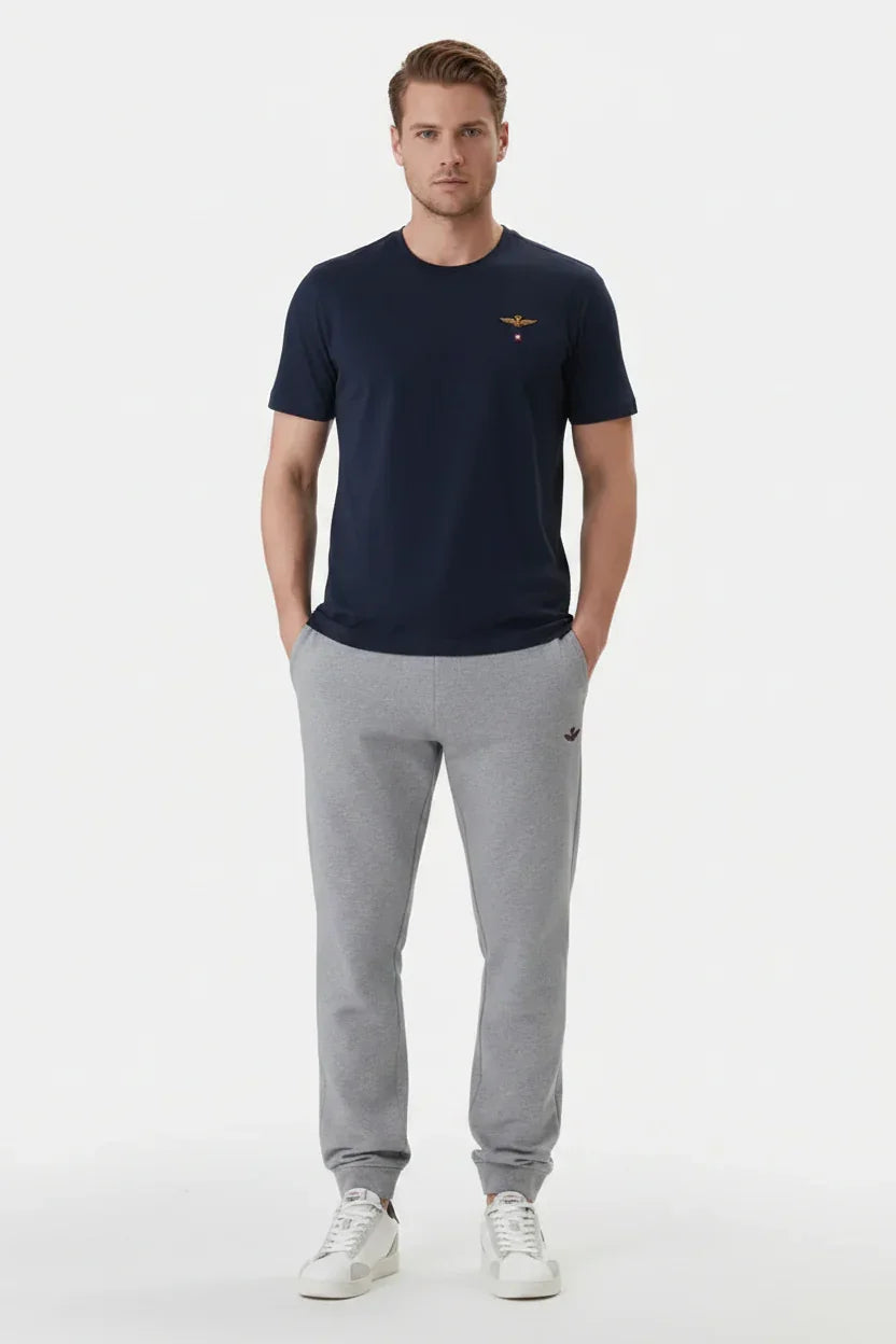 Modello indossa t-shirt blu scuro regular fit e pantaloni grigi sportivi uomo