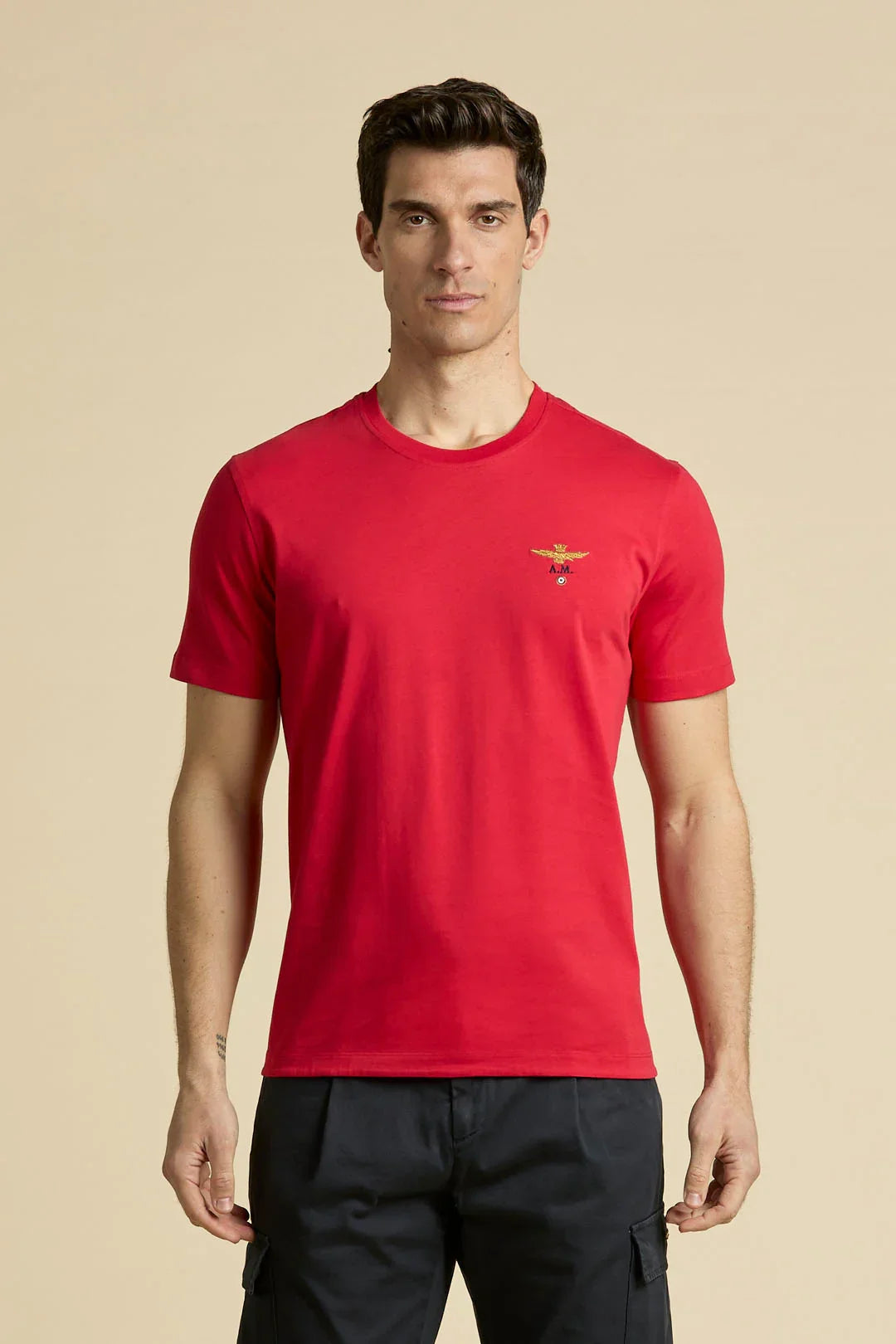 Modello indossa t-shirt uomo rossa a maniche corte con girocollo e piccolo logo sul petto