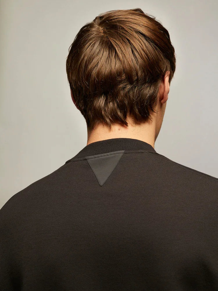 Dettaglio retro felpa uomo nera con applicazione triangolare, moda abbigliamento maschile