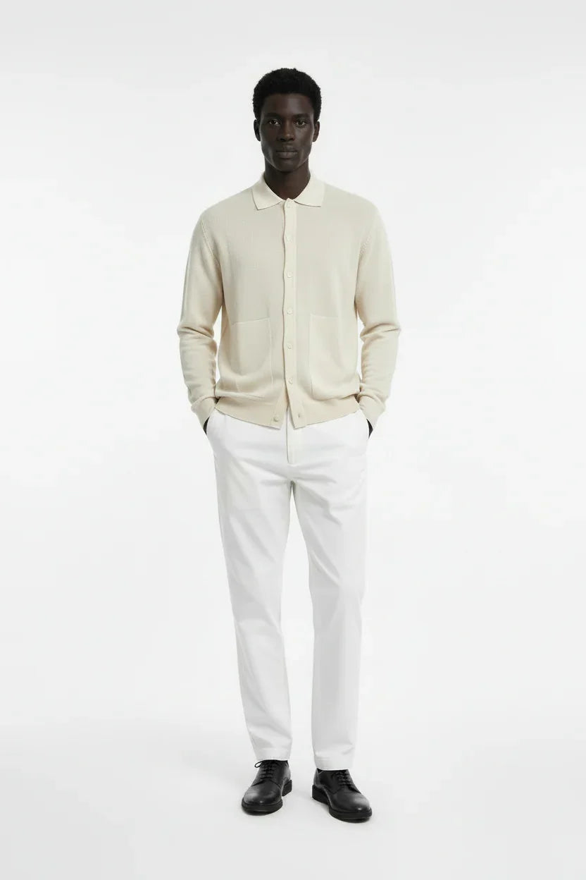 Modello uomo con cardigan beige, pantaloni bianchi eleganti e scarpe nere, moda uomo elegante.