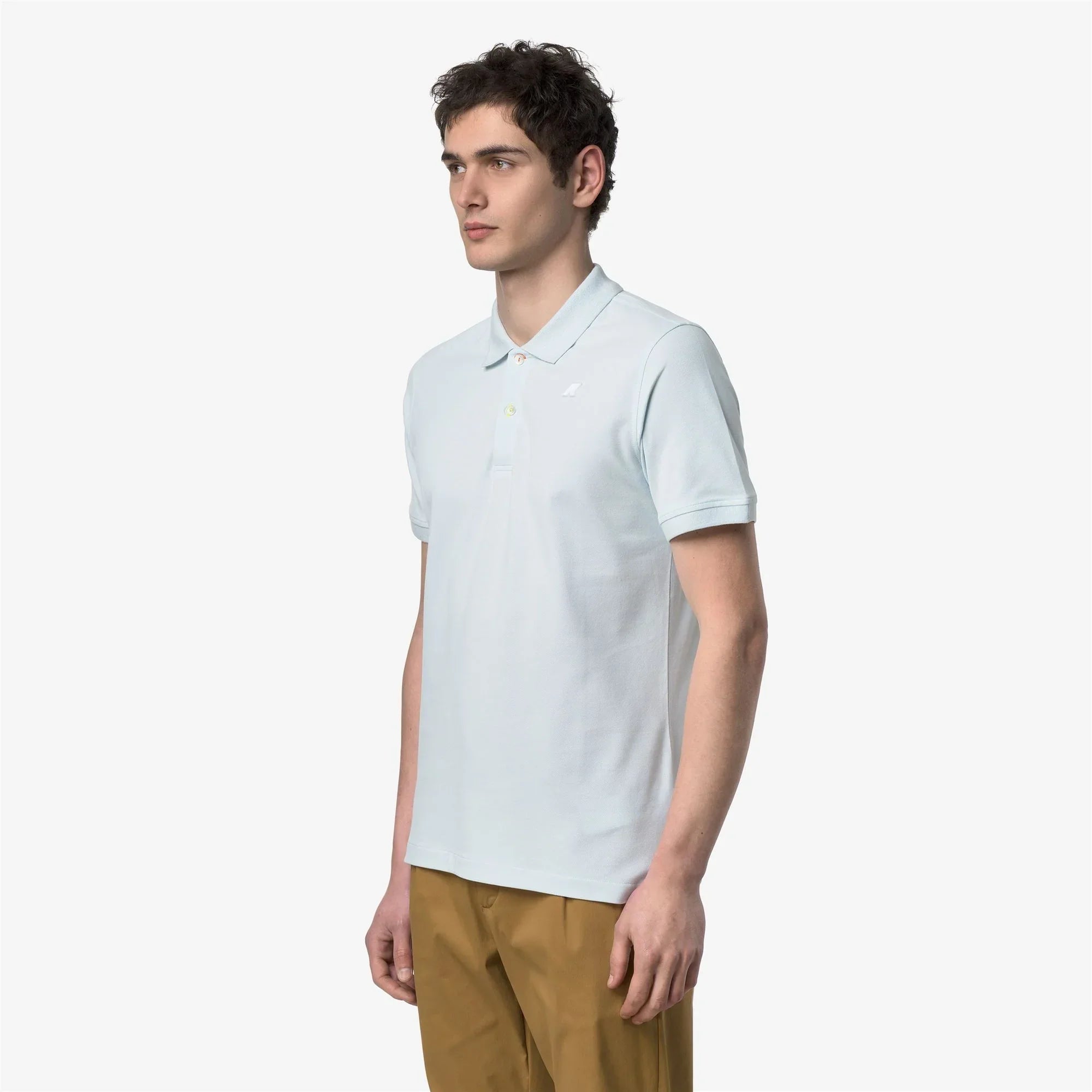 Modello indossa polo uomo azzurra manica corta con pantaloni beige, stile casual elegante.