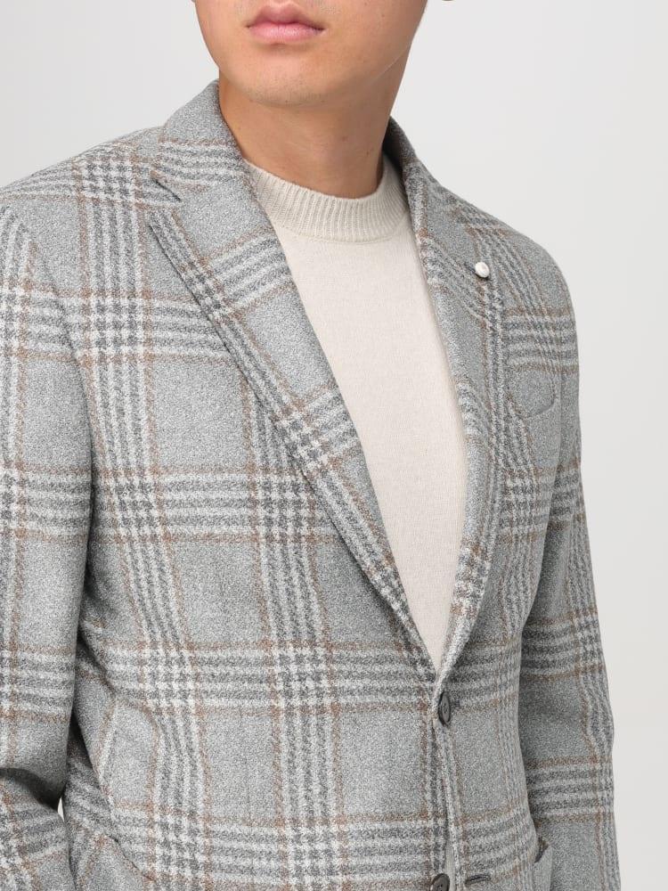Giacca uomo grigia a quadri eleganti, indossata su maglione beige chiaro, moda uomo.