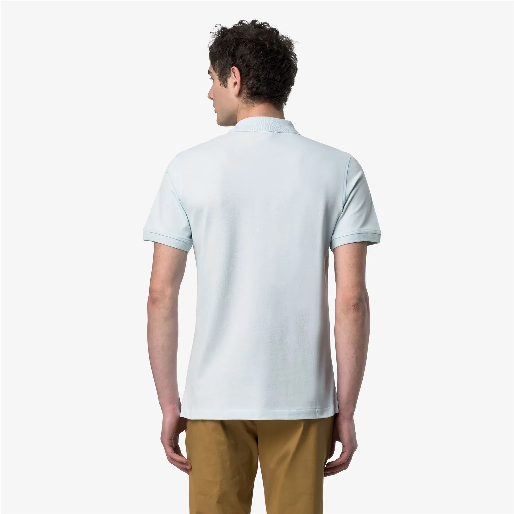 Uomo di spalle indossa polo celeste a maniche corte e pantaloni beige, moda uomo casual.
