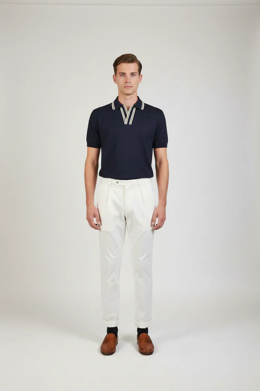 Uomo con polo blu scuro a maniche corte e pantaloni bianchi eleganti, look moda uomo.